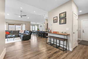Living room featuring dark wood-type flooring, a ceiling fan, recessed lighting, and lofted ceiling