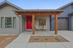 View of exterior entry featuring covered porch, a garage, and concrete driveway
