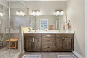 Full bath featuring double vanity, a shower stall, and light tile patterned flooring