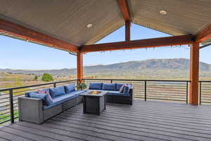 Deck with a mountain view and an outdoor living space with a fire pit