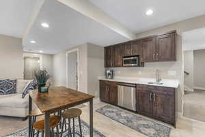 Kitchen with dark wood finish cabinets, recessed lighting, stainless steel appliances, open floor plan, and light stone countertops