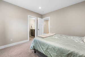 Bedroom with light carpet, ensuite bathroom, and recessed lighting