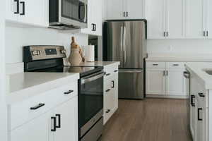 Kitchen with stainless steel appliances, white cabinets, and dark wood finished floors
