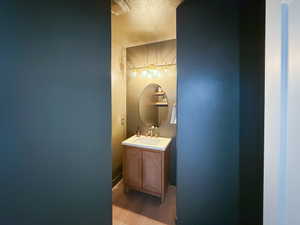 Half bathroom with vanity, a textured ceiling, and light wood-style flooring