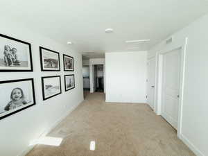 Hall featuring light carpet and a textured ceiling