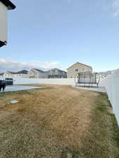 Fenced backyard featuring a trampoline and a residential view