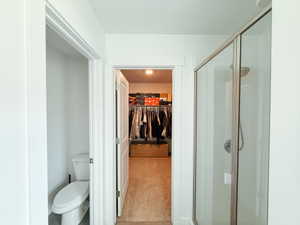 Bathroom with a spacious closet, a stall shower, and light colored carpet