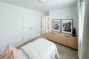 Bedroom with light carpet and a closet