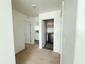 Hallway featuring light carpet and a textured ceiling
