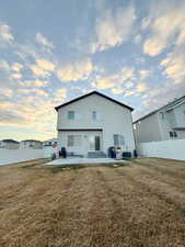 Back of property at dusk featuring a patio area