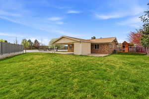Rear view of house featuring a fenced backyard, a patio area, and brick siding