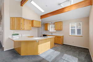Kitchen with a peninsula, dark colored carpet, light countertops, vaulted ceiling, and light wood finish cabinets