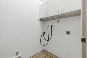 Laundry area featuring hookup for a washing machine, cabinet space, electric dryer hookup, and light wood-style floors