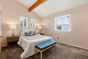 Carpeted bedroom with lofted ceiling with beams and multiple windows