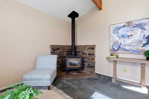 Detailed view of a wood stove, carpet, and beamed ceiling