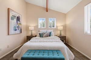 Bedroom with vaulted ceiling with beams and dark colored carpet