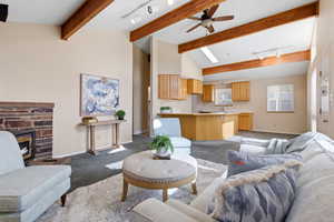 Carpeted living area with track lighting, a ceiling fan, vaulted ceiling, and a fireplace