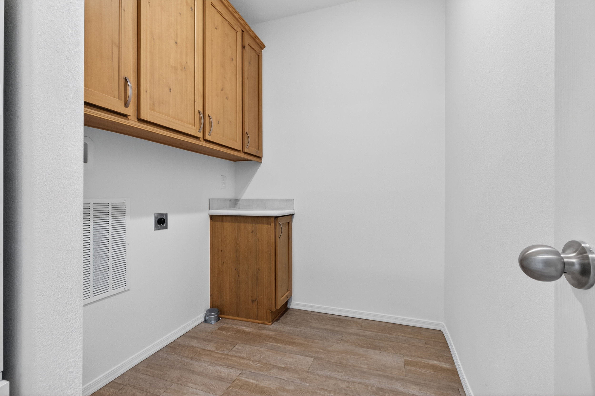 Laundry room featuring electric dryer hookup, cabinet space, and light wood-style floors