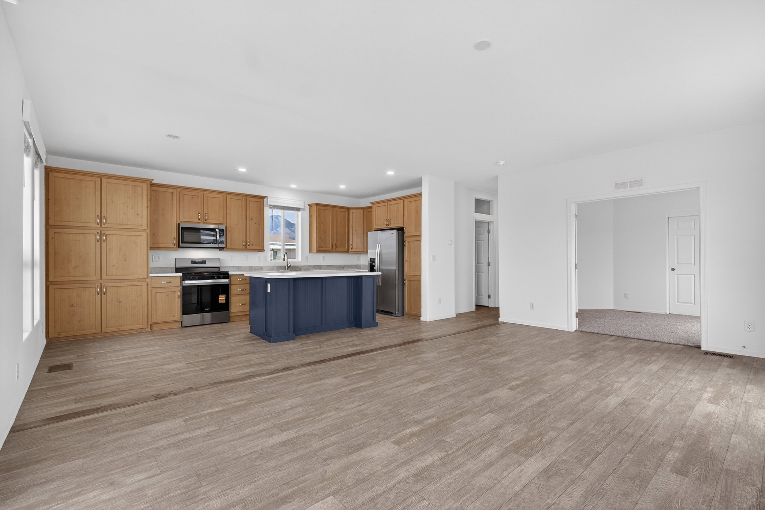 Kitchen featuring open floor plan, stainless steel appliances, light countertops, light wood-style flooring, and a center island