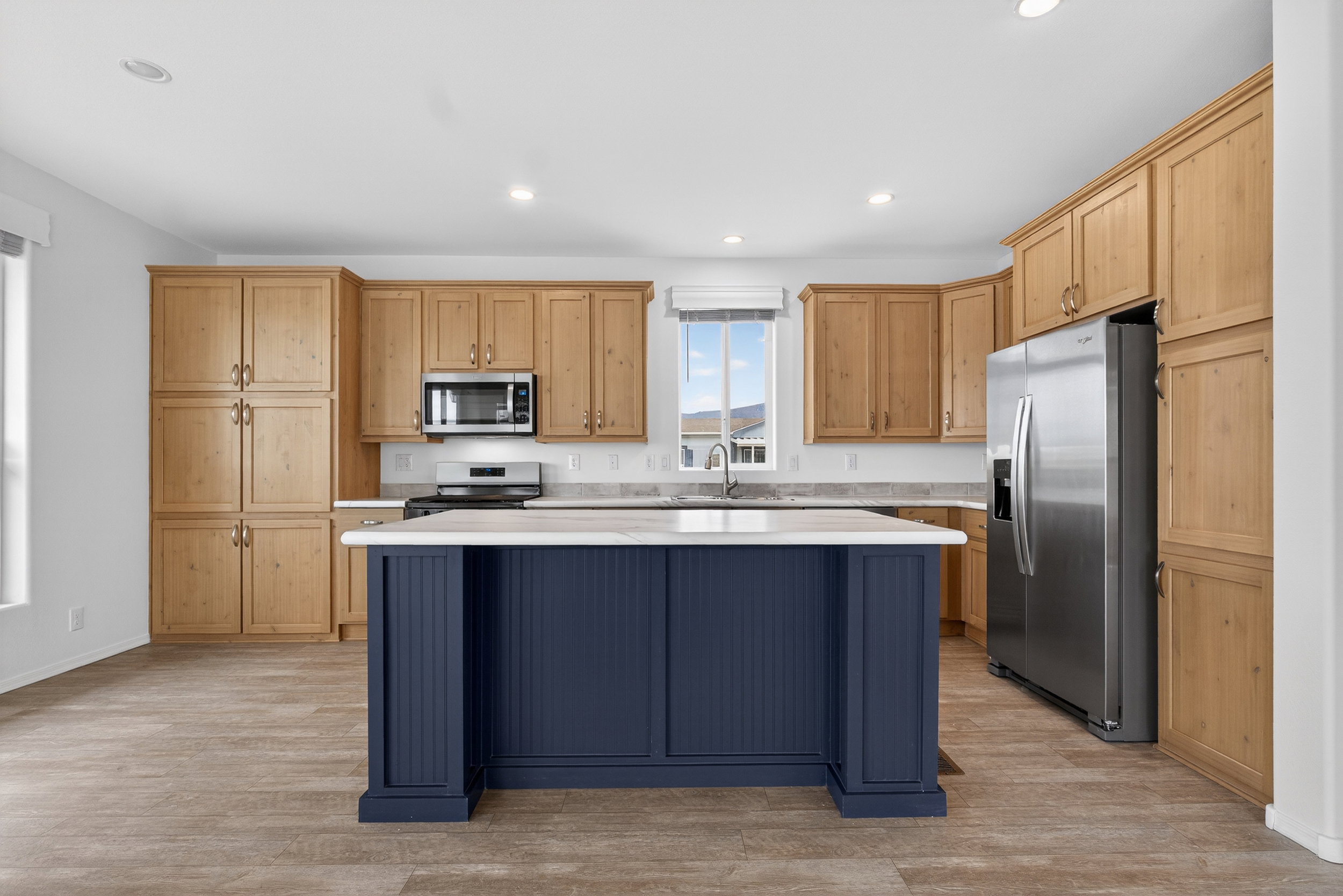 Kitchen featuring stainless steel appliances, a center island, light wood-type flooring, light wood finish cabinets, and recessed lighting