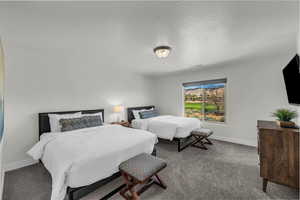 Carpeted bedroom featuring a textured ceiling and baseboards