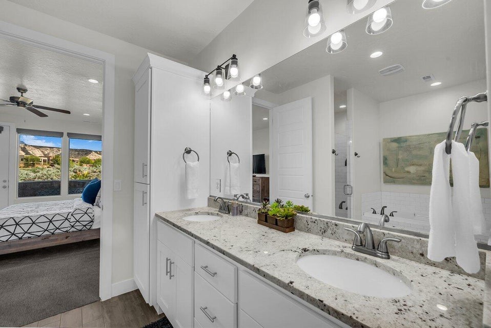 Ensuite bathroom with double vanity, a stall shower, a garden tub, ceiling fan, and dark wood finished floors