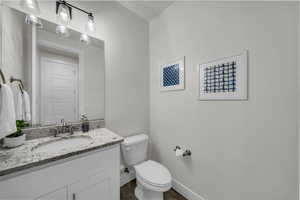 Half bath featuring vanity and dark wood-type flooring