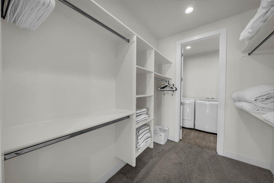 Walk in closet featuring separate washer and dryer and dark carpet
