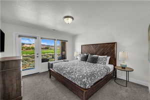 Bedroom with a textured ceiling, access to exterior, and dark carpet