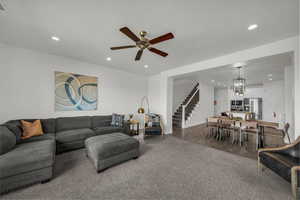 Living area featuring ceiling fan, carpet flooring, suspended lighting, and a textured ceiling