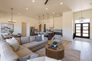 Living room with hanging lights, light wood-type flooring, and french doors