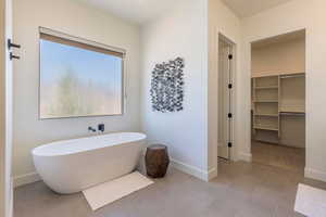 Full bath with a freestanding bath and a walk in closet