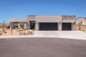 View of front of house featuring stone siding, stucco siding, an attached garage, concrete driveway, and a mountain view