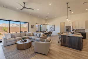 Living area featuring ceiling fan, light wood-type flooring, a high ceiling, hanging lights, and a mountain view
