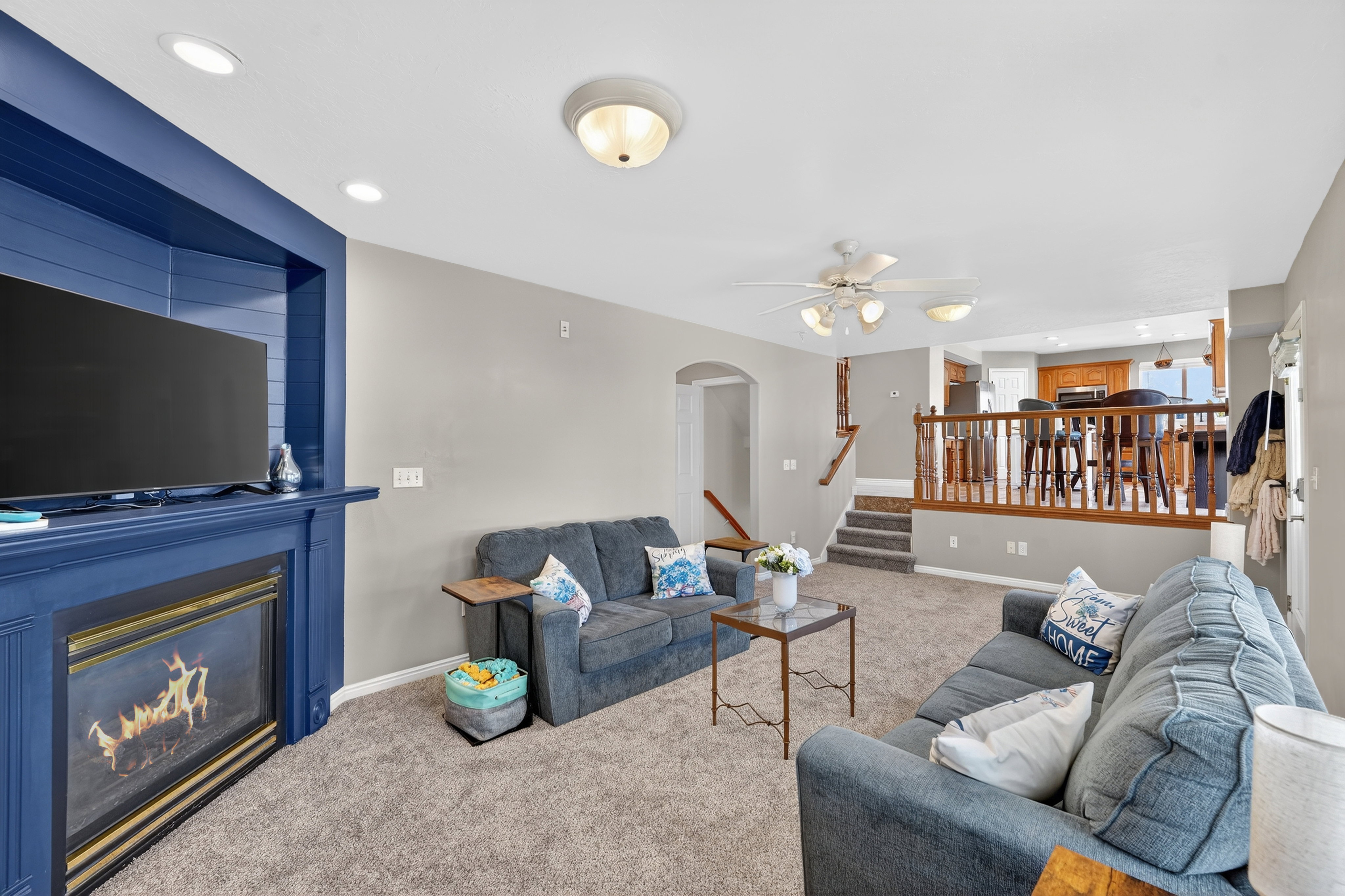Living area with arched walkways, carpet flooring, recessed lighting, ceiling fan, and a large fireplace