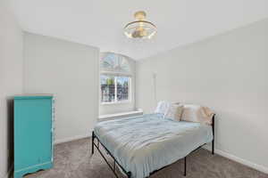 Carpeted bedroom with a chandelier and baseboards