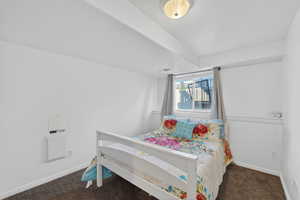 Bedroom featuring baseboards and dark colored carpet