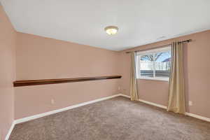 Empty room with light colored carpet and baseboards