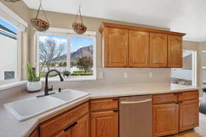 Kitchen featuring dishwasher, a mountain view, light countertops, wood finish cabinetry, and hanging light fixtures