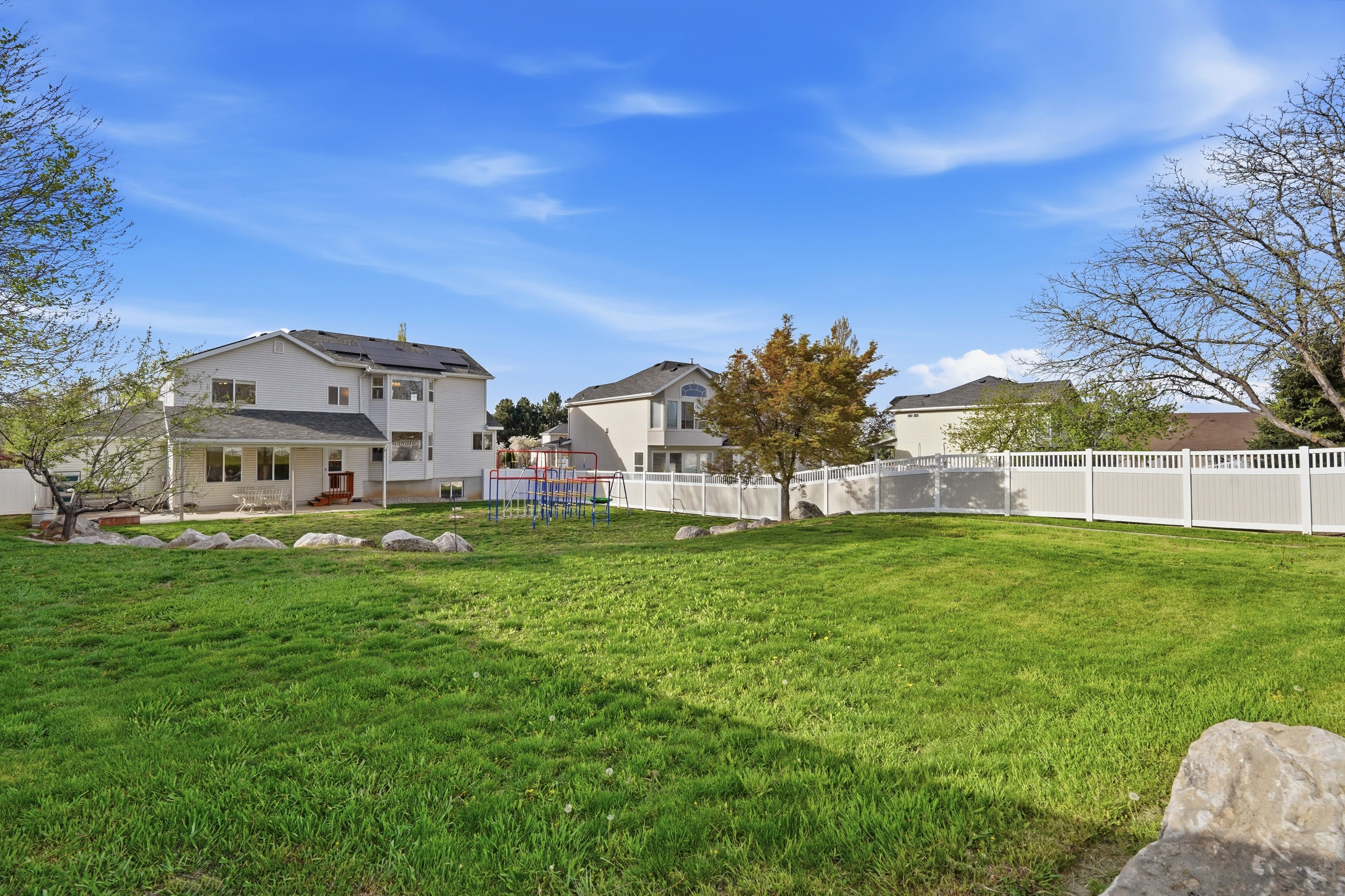 Fenced backyard with a playground and a patio area