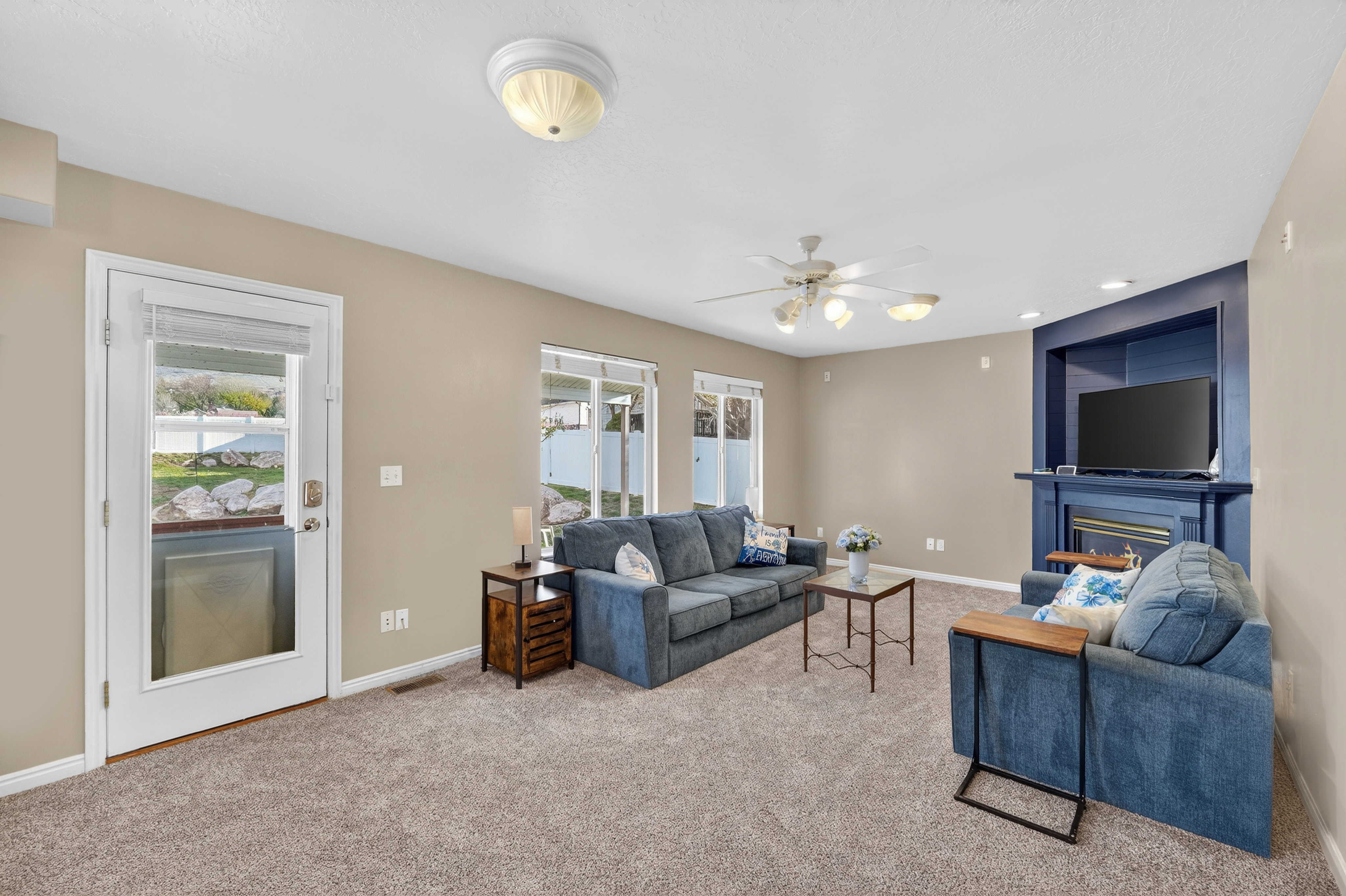 Carpeted living room featuring healthy amount of natural light, a glass covered fireplace, ceiling fan, and recessed lighting
