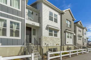View of front of home featuring stone siding, a balcony, and board and batten siding