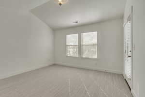 Spare room with light colored carpet and lofted ceiling