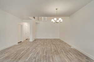 Spare room featuring light wood-type flooring and hanging lights