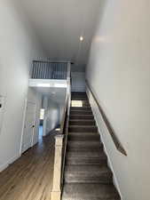 Staircase with wood finished floors, a high ceiling, and recessed lighting