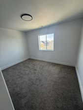 Empty room featuring dark carpet and baseboards