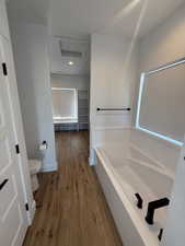 Full bath featuring a bath and light wood-type flooring