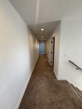 Corridor featuring dark colored carpet, recessed lighting, and an upstairs landing