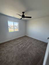 Empty room with dark carpet and ceiling fan
