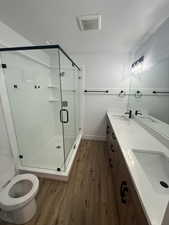 Bathroom with dark wood-style flooring, double vanity, a shower stall, and a textured ceiling